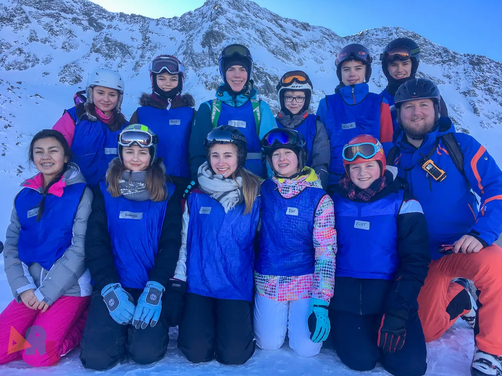Gruppe kniet und steht für ein Foto im Schnee.